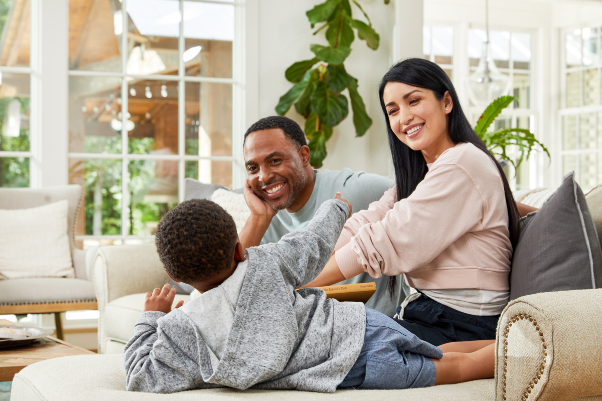 Commercial lifestyle photography of family in living room playing and smiling at their son.