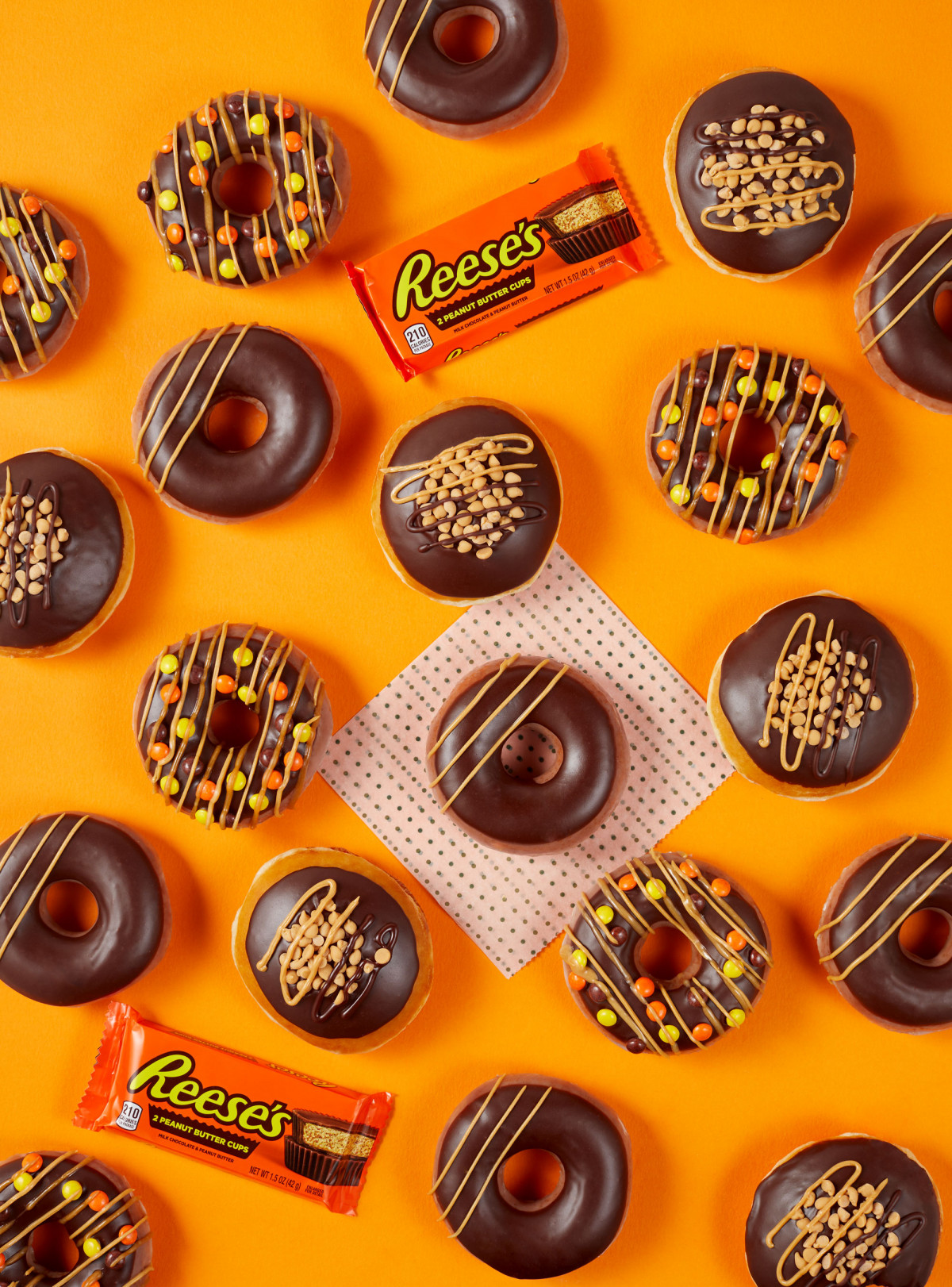 Commercial food photography of Krispy Kreme Reese's Doughnuts on an orange background