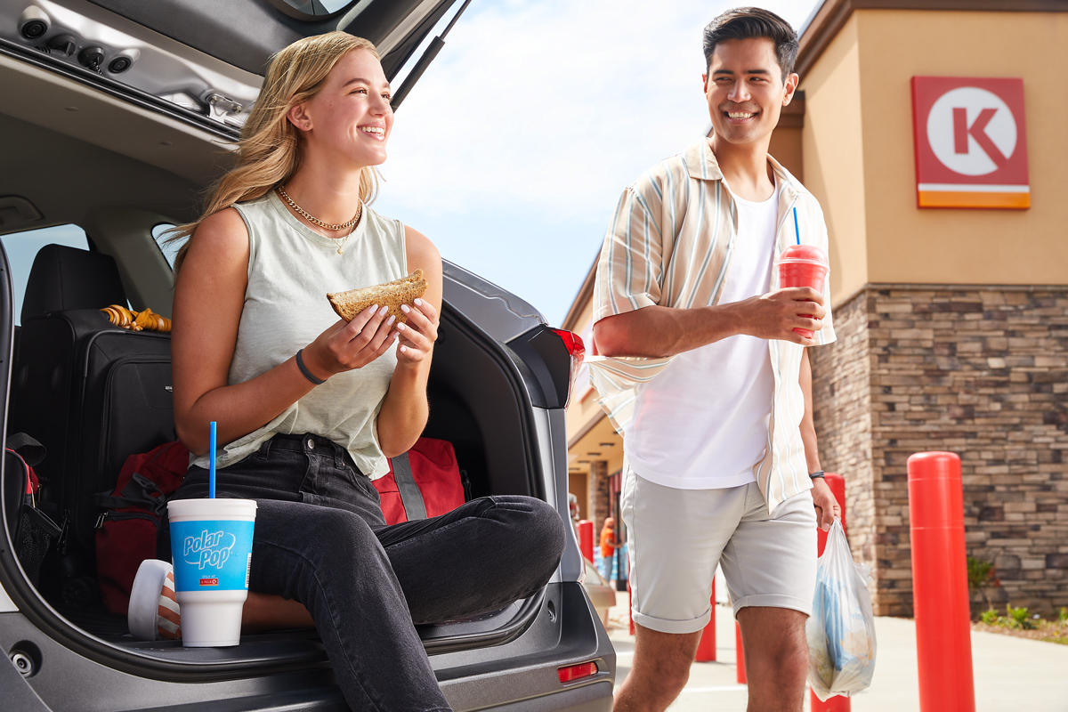 commercial lifestyle photography of professionally styled man and woman at Circle K stores enjoying carryout soda and sandwiches on the back of their car.