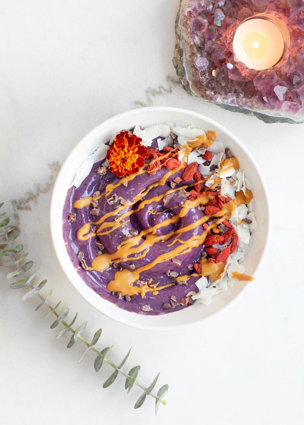 food lifestyle photo of purple smoothie bowl topped with goji berries and seeds