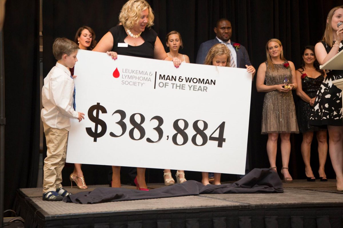 Corporate event photography of a woman holding a large ceremonial check for a charity
