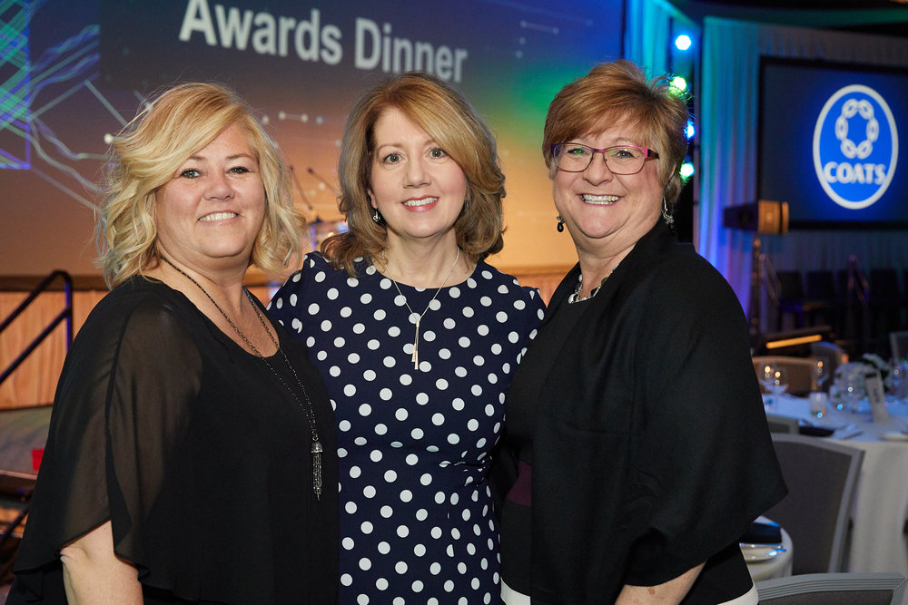 Three women posing for a photo at a corporate event